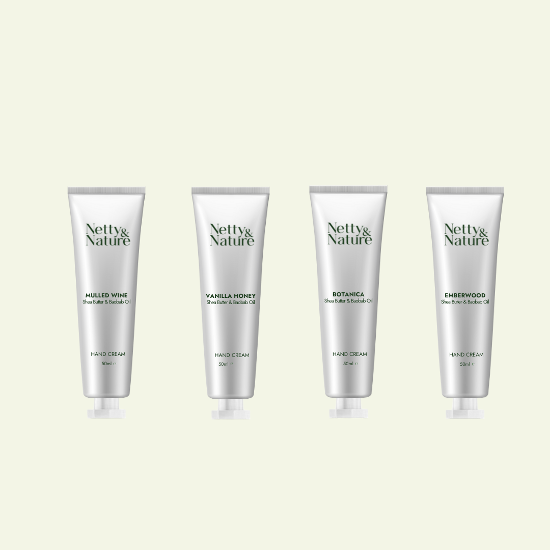 Four Netty & Nature travel-size hand cream tubes standing in a row